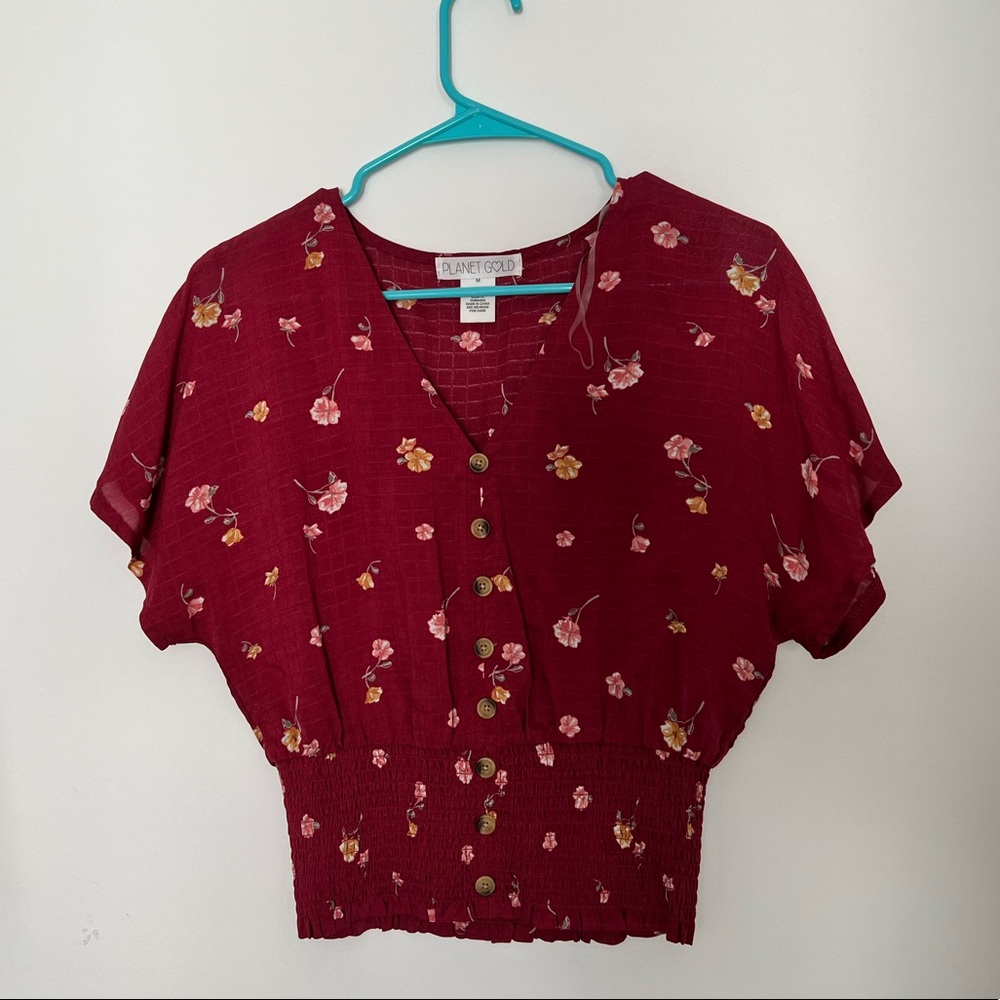 A maroon colored blouse with flower detailing all over. Never worn.